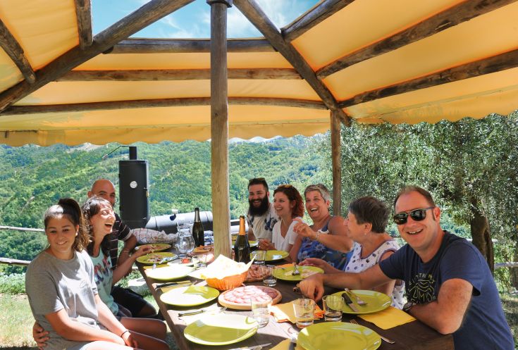 Un déjeuner avec des amis dans un agriturismo au milieu de la verdure, entouré d'arbres et de nature.