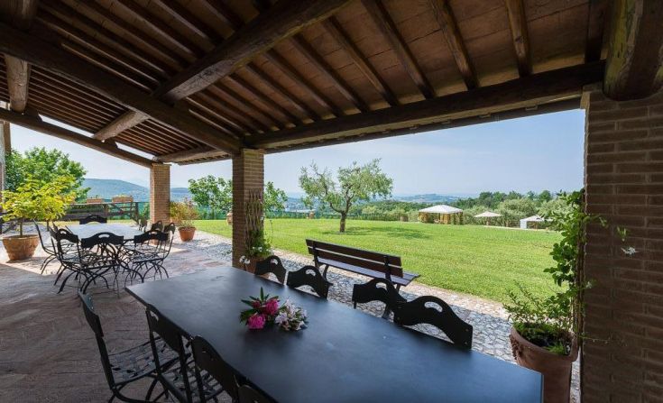 An outdoor area overlooking a large garden, equipped with tables and chairs for relaxation.