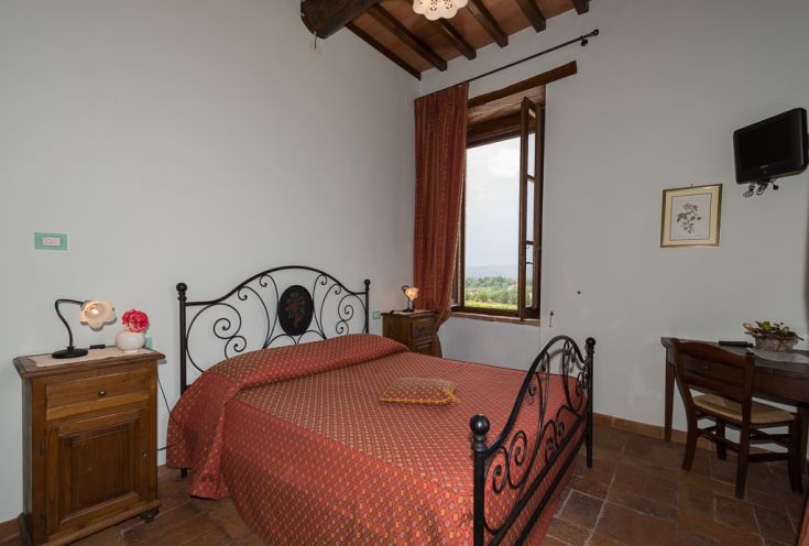 Cozy room with a double bed and rustic decor. The exterior view features a serene landscape.