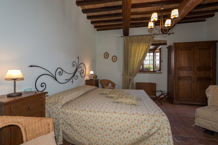 A simple and warm bedroom, furnished with wooden furniture and some floral accents.