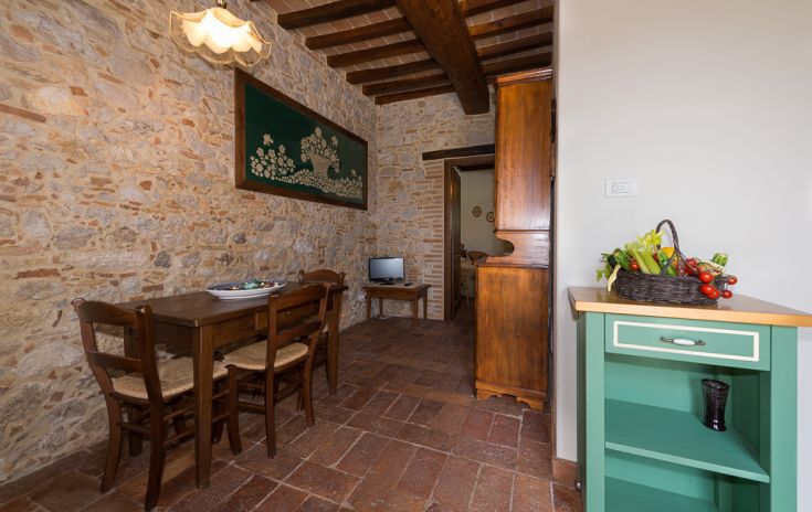 A rustic apartment corner featuring stone walls and a wooden table in a simple setting.