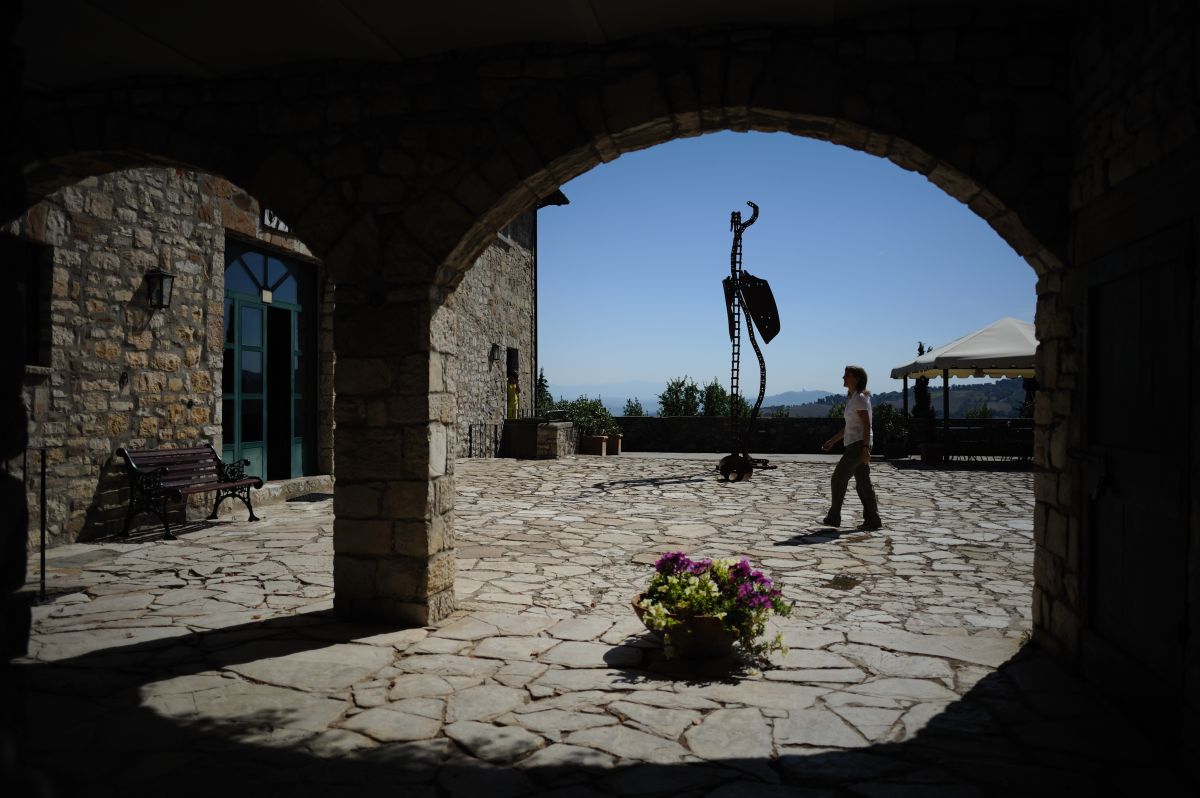 Un cortile sereno, con una scultura intrigante; un uomo passeggia vicino ad essa.