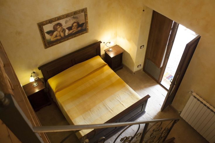 Chambre simple avec un lit double et des meubles en bois, parfaite pour un séjour tranquille.