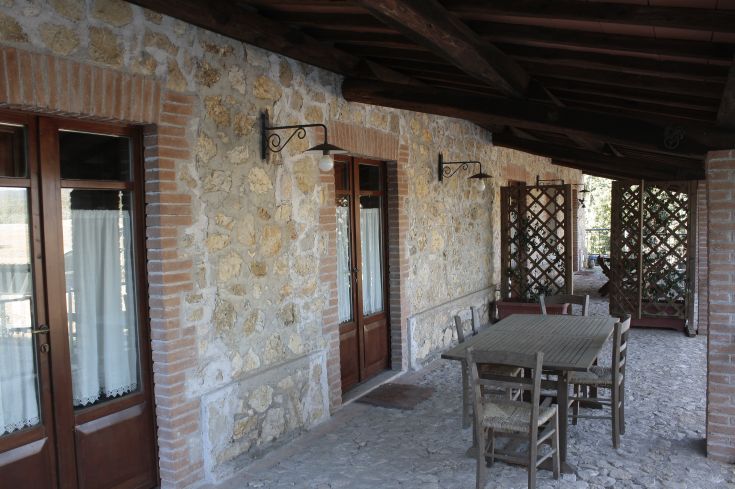 Zone extérieure d'une ferme offrant une table et des chaises en bois, entourée d'un environnement naturel et paisible.