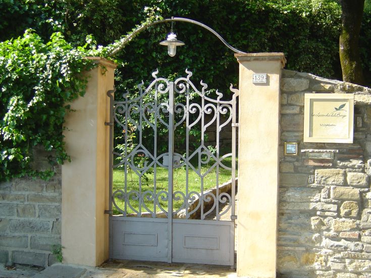 Charakteristische Eingangstür eines historischen Palastes, umgeben von Vegetation und grünen Rasenflächen.