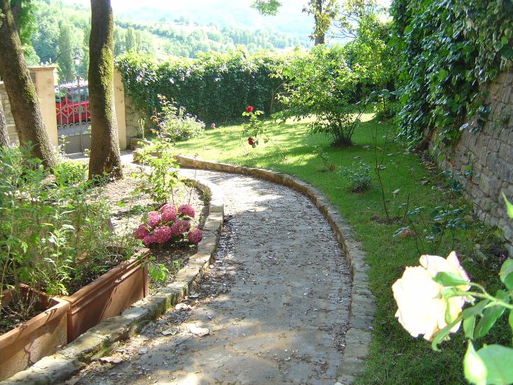 Ein gepflegter Garten mit einem Weg, der sich zwischen blühenden Pflanzen schlängelt und eine ruhige Atmosphäre schafft.