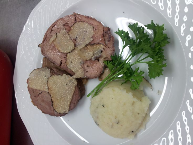 Ein Fleischgericht, serviert mit Kartoffelbrei, garni mit Trüffeln und Petersilie.