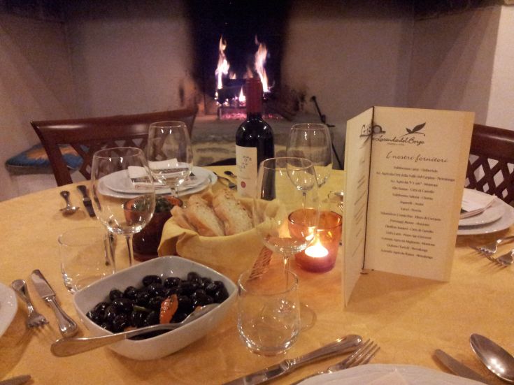 Elegante Dekoration für ein Dinner am Kamin, mit Weinen und Vorspeisen. Warme und entspannende Atmosphäre.