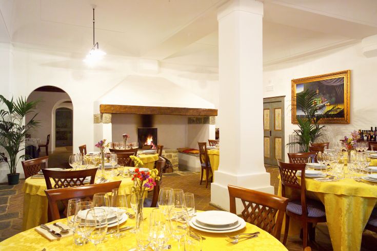 Ein einfaches Esszimmer mit schön eingedeckten Tischen und einem brennenden Kamin.