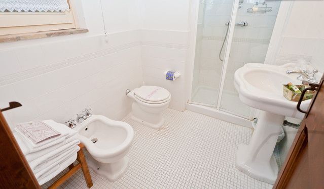 Funktionales Badezimmer mit Dusche, Waschbecken und Bidet, praktisch eingerichtet.