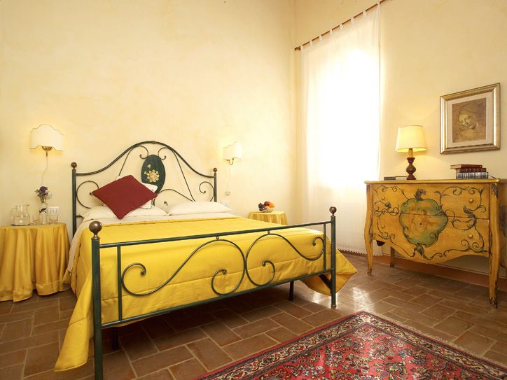 Ein warmes und gemütliches Zimmer mit einem schmiedeeisernen Bett, gelben Möbeln und klassischen Elementen.