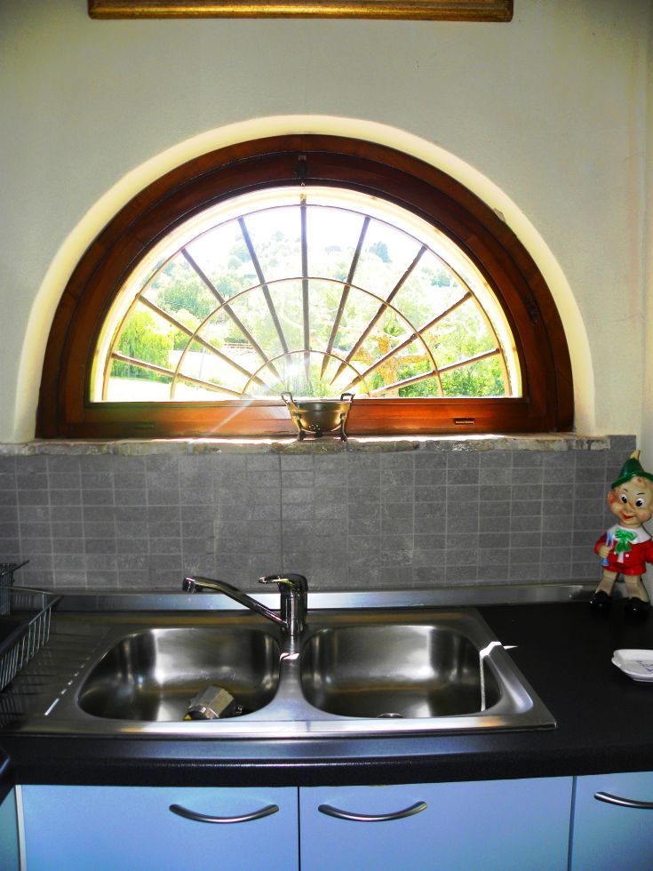 Kitchen with a view of the Umbrian hills and simple furnishings.