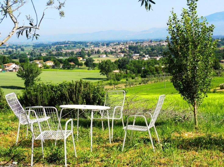 A serene landscape of green hills, featuring a table and chairs set up for relaxation in nature.