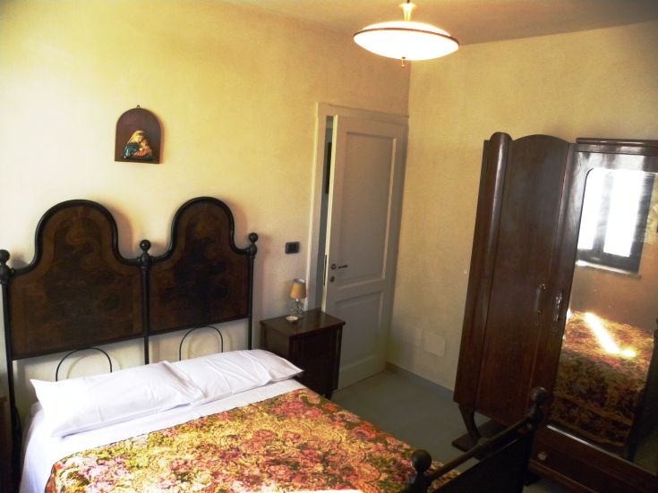 An intimate space with a double bed and wooden furniture, featuring a calm atmosphere.