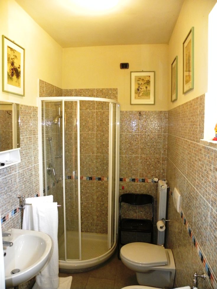 A rustic bathroom with a shower and simple furnishings, located in a natural setting of Umbria.