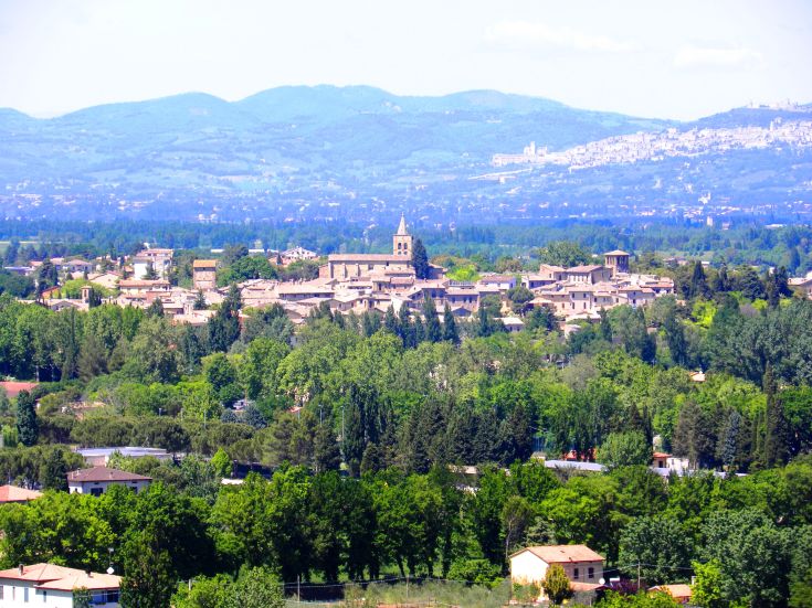 A serene scene of an Umbrian town, surrounded by rolling green hills.