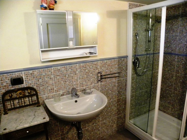 A simple and well-furnished bathroom featuring a shower, sink, and mirror, focusing on details.