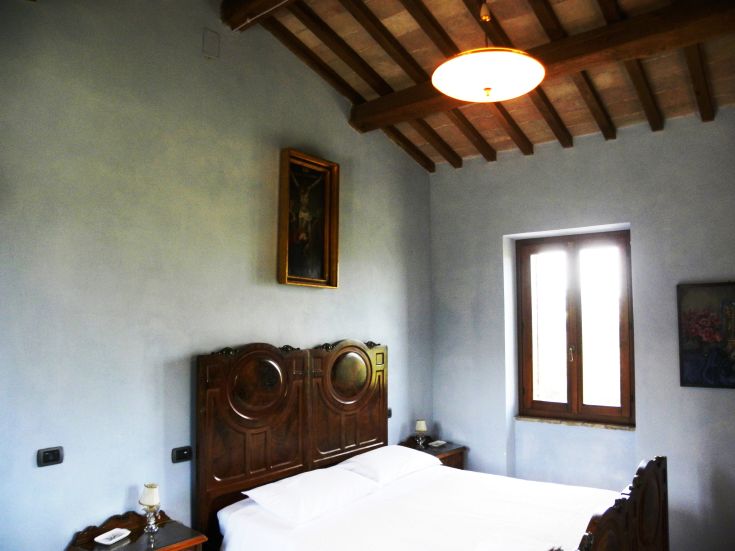 A simple room in an Umbrian palace, featuring rustic furnishings and a relaxing atmosphere.