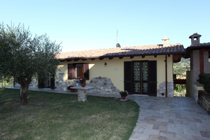 Un agriturismo circondato da un giardino con alberi e ampio spazio esterno per il relax.