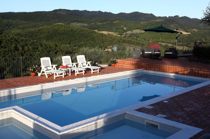 Piscina di un agriturismo immersa tra dolci colline verdi.