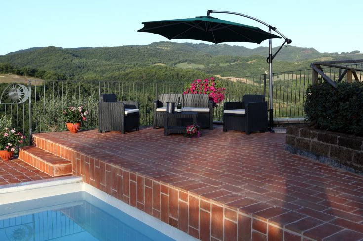 Una terrazza spaziosa con piscina, affacciata su dolci colline circostanti.