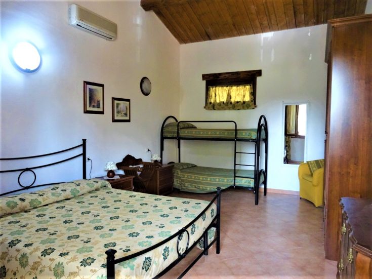 Cozy room with a double bed and bunk beds, furnished with simple and functional decor.