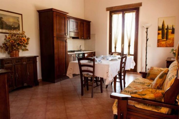 Interior of an apartment featuring a kitchenette and dining area, lit by natural light, creating a cozy atmosphere.