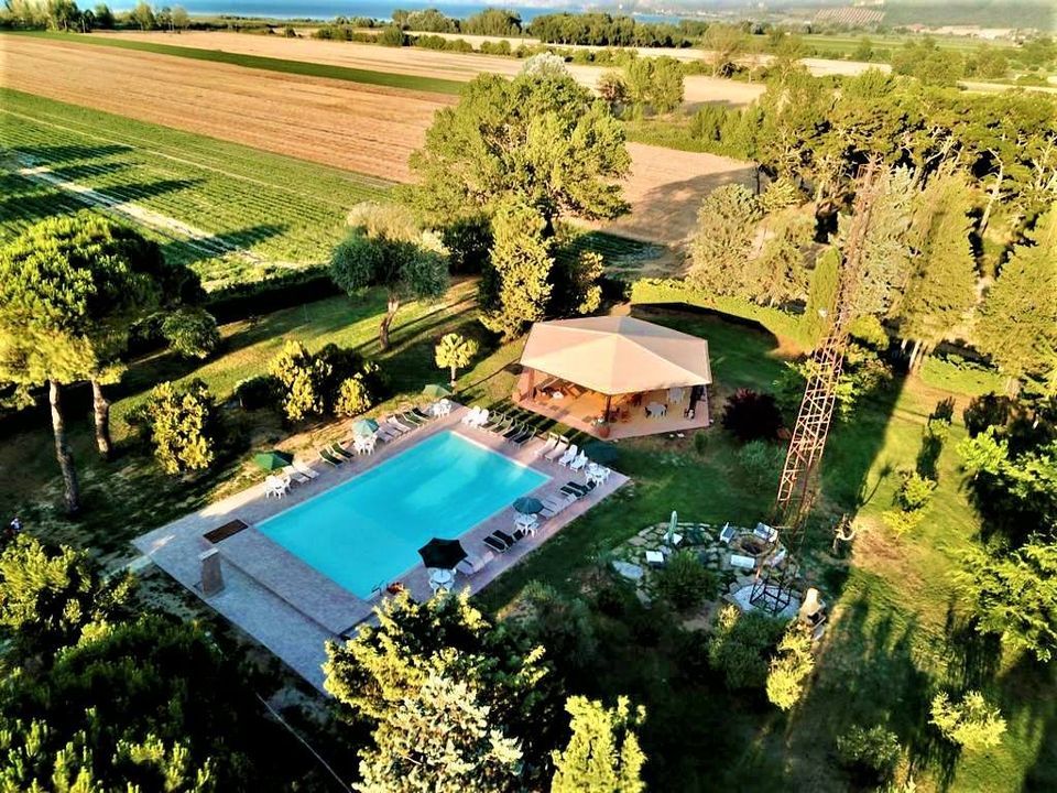 Vue aérienne d'une résidence avec piscine, entourée de verdure, d'arbres et de pelouses.