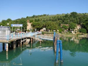 Un pontile che porta all'Isola Maggiore, immerso in un paesaggio lacustre di verde vivace.