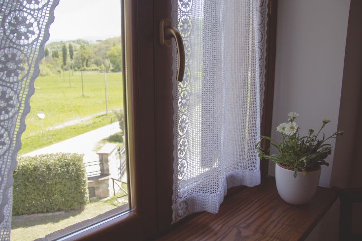 A scenic view from a window overlooking green hills and plants in a characteristic Umbrian palace.