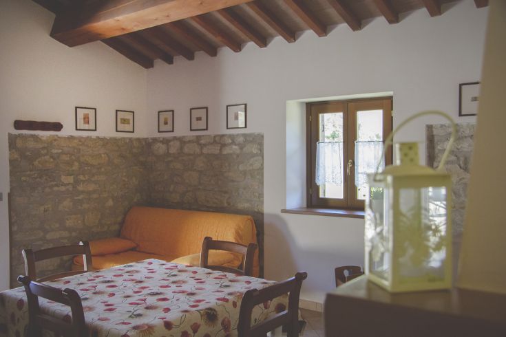 A cozy interior featuring a sofa and a table, showcasing typical elements of Umbrian architecture.
