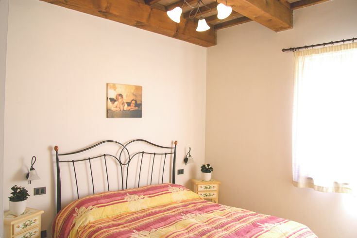 Simple room with a bed, small plants, and a window allowing natural light in.