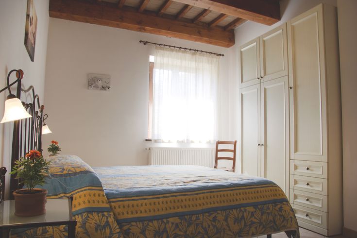 Simple bedroom with a bed and wardrobe, well-lit by natural daylight.