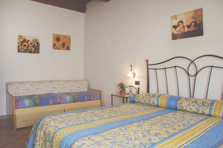 Simple room with a double bed and a sofa bed, enhanced with some decorations.