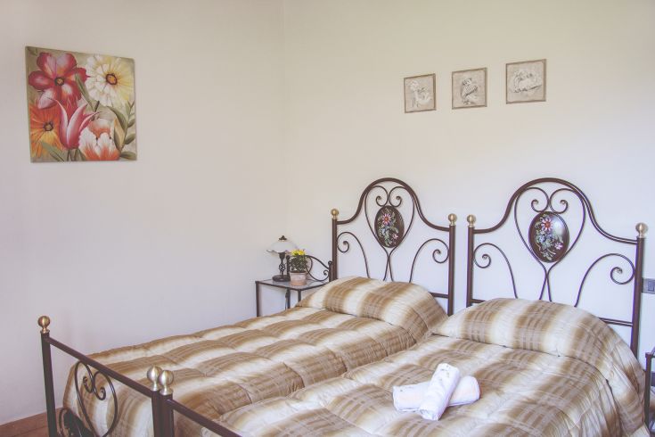 Simple room with twin beds, lit by warm tones and floral decorations.