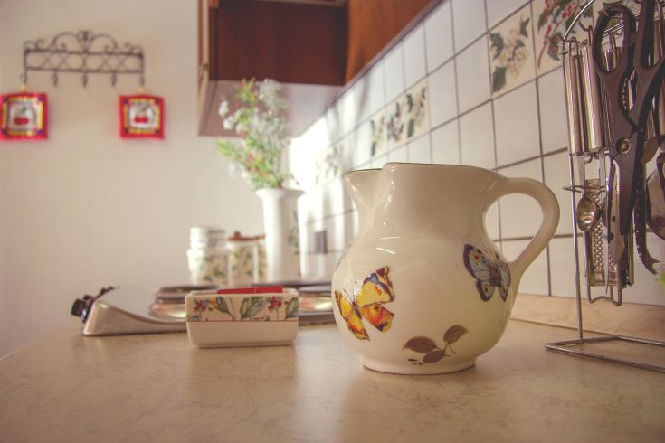 A simple kitchen corner with decorated ceramics and a long vase on the countertop.