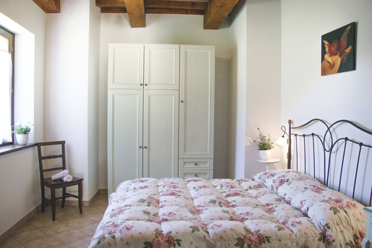 A simple bedroom with a double bed and floral decorations, perfect for a peaceful stay.