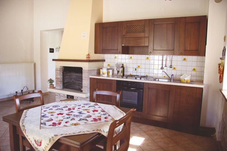 Cozy kitchen with wooden furniture and floral details, perfect for gatherings and quality time.