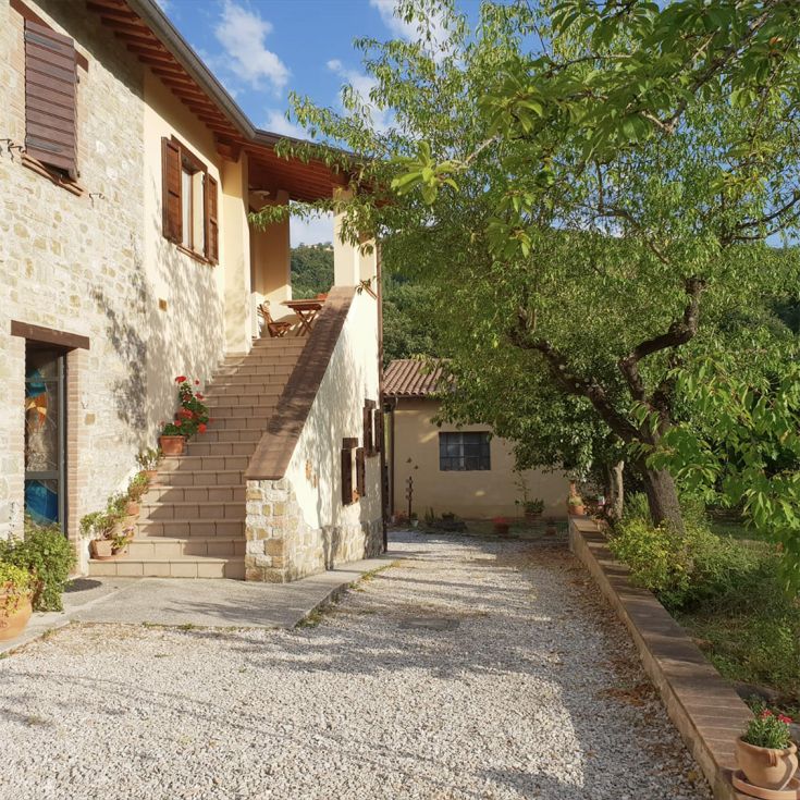 Umbrian building with apartments, garden, and dog area surrounded by greenery.