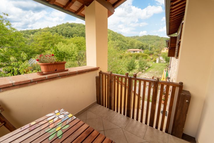 In a serene corner of Umbria, a balcony overlooks green hills and a well-kept garden.