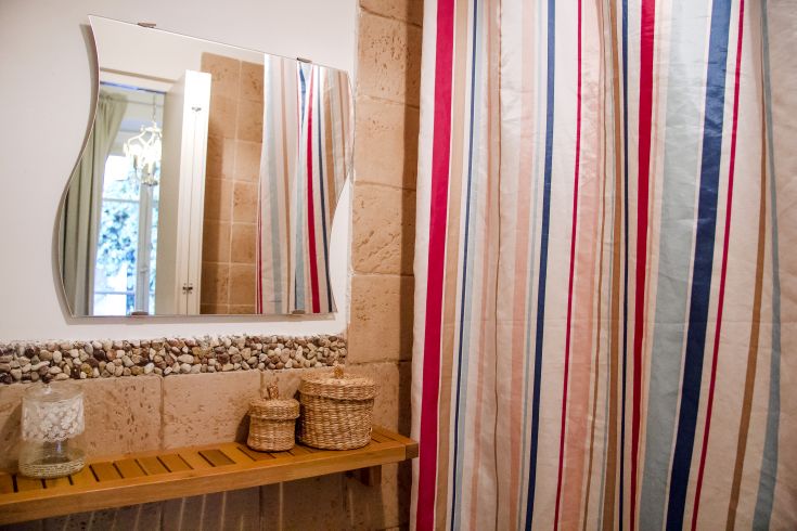 A simple bathroom with a mirror, striped curtains, and wooden materials.