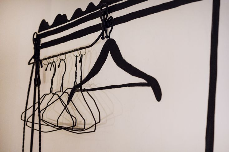 A simple coat rack mounted on a wall, featuring metal hooks for hanging coats and jackets.
