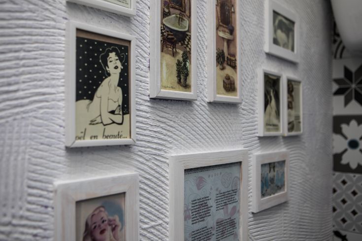 A wall adorned with vintage white frames showcasing carefully selected photographs and prints.