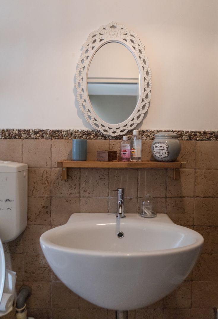 A well-furnished contemporary bathroom featuring a modern sink, simple mirror, and personal care accessories.