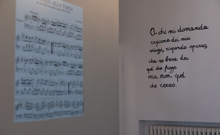 Musical notes with a poetic quote written on a wall in a simple setting.
