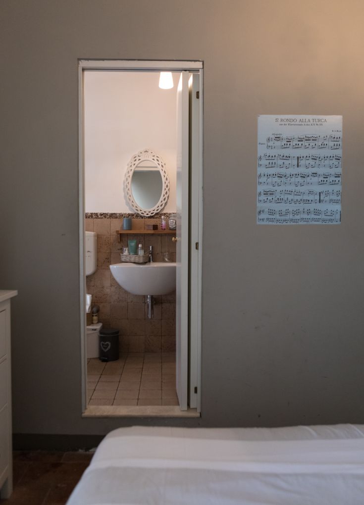 A sober bathroom interior featuring a mirror and a music poster. The atmosphere is calm and inviting.