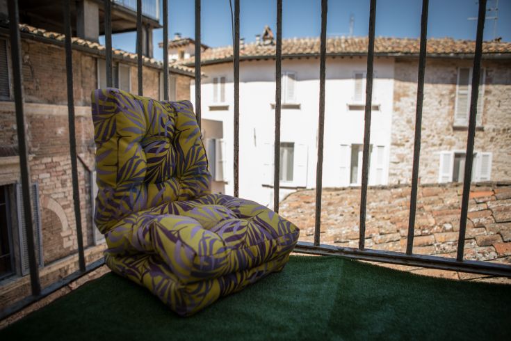 A colorful armchair on a balcony with a view of the historic center.