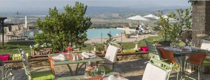 Restaurant en plein air niché dans la campagne ombrienne, avec une piscine visible en arrière-plan.