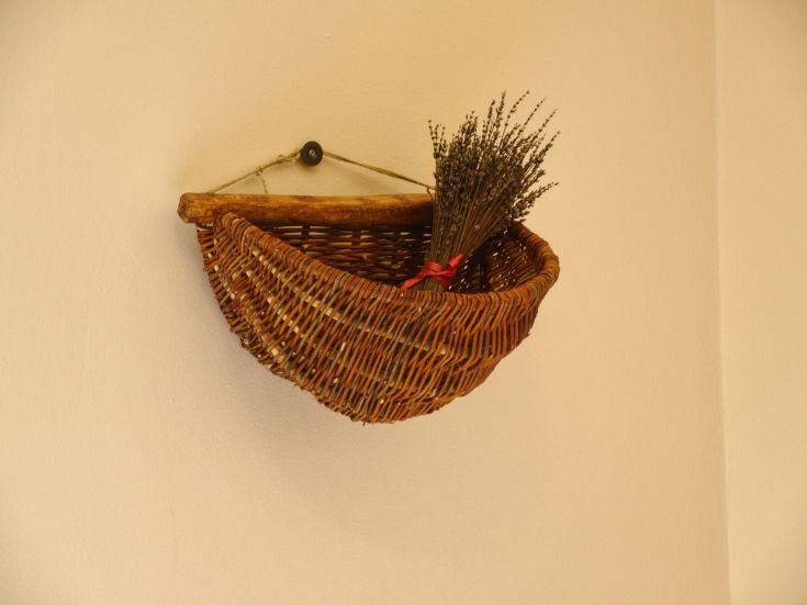 A woven basket hanging on the wall, filled with lavender flowers, creating a simple and welcoming atmosphere.