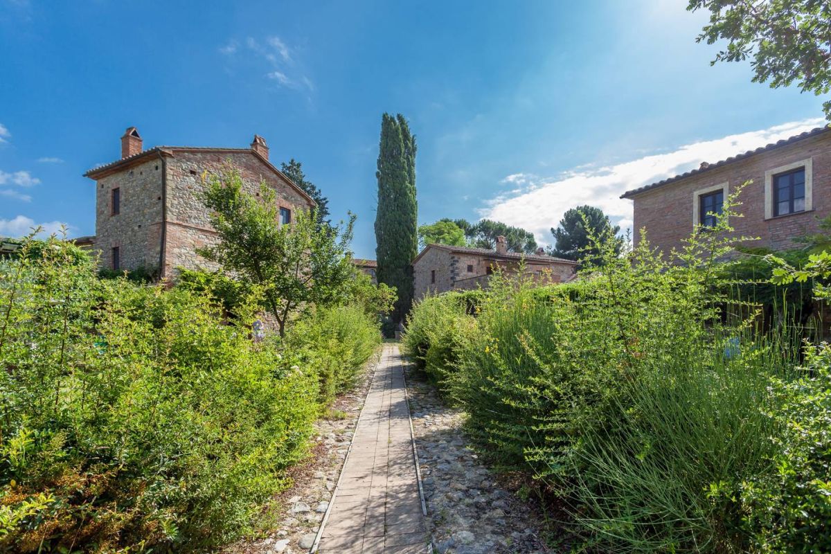 A rural village immersed in the green of Umbria, featuring historic houses and abundant vegetation.
